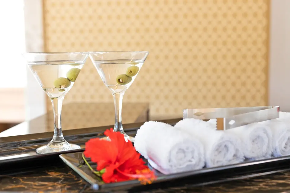 Two martini glasses, rolled towels, and a red flower at Royalton Grenada.