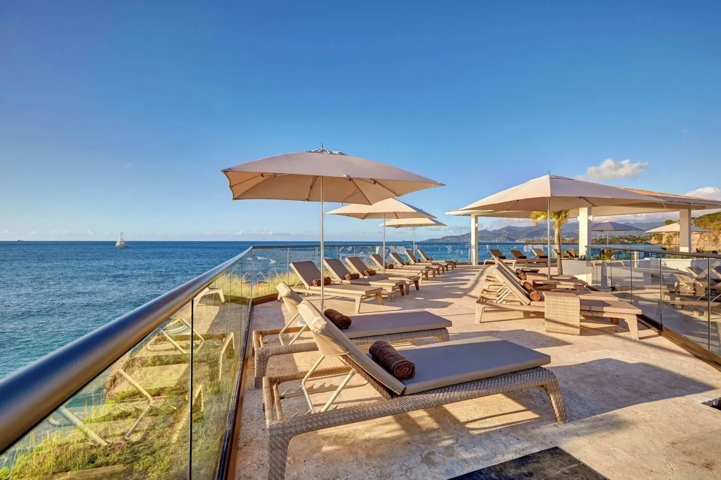 Ocean-view sun deck with loungers and umbrellas at Royalton Grenada.