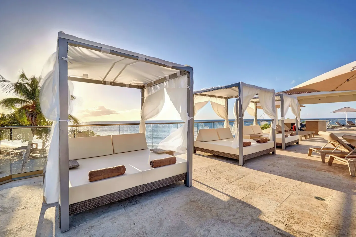 White cabana beds and umbrellas on an oceanfront terrace at Royalton Grenada.
