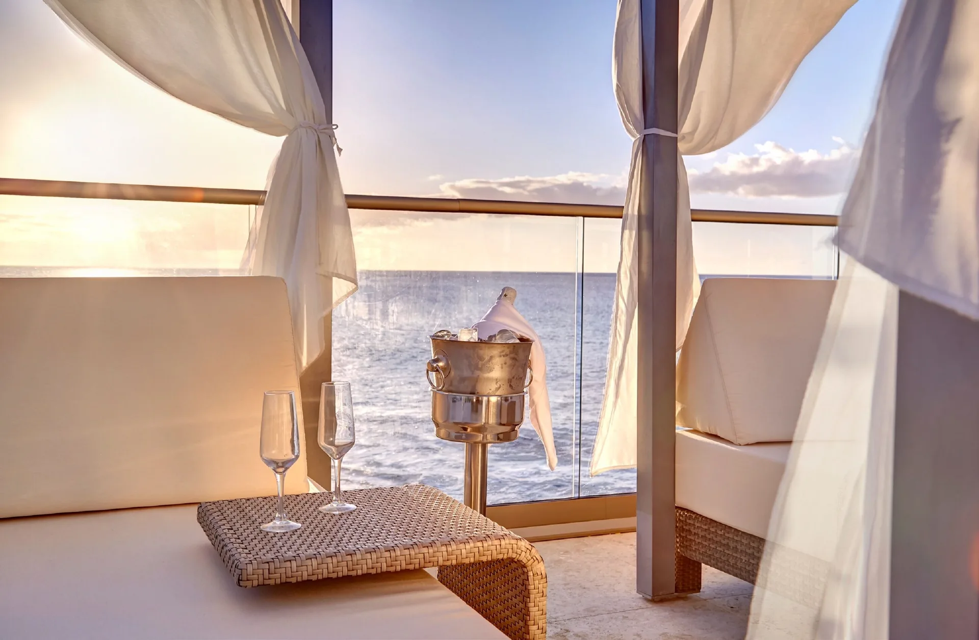Oceanfront cabana seating with glasses and an ice bucket at Royalton Grenada.
