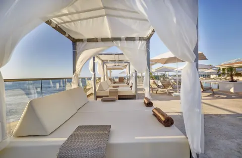 Oceanfront cabana bed with white drapes on a sun deck at Royalton Grenada.