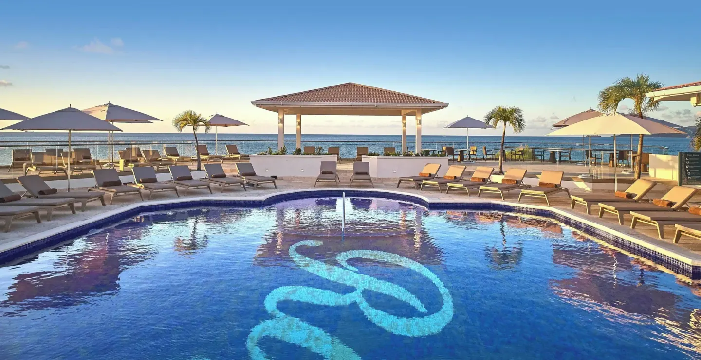 Oceanfront pool with loungers, umbrellas, and gazebo at Royalton Grenada.