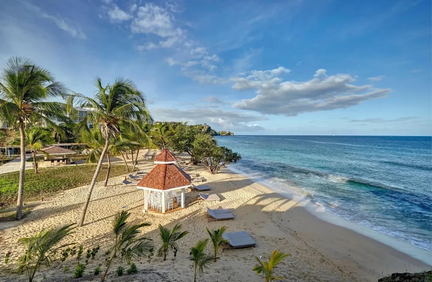 Palm-lined beach with loungers and a small gazebo at Royalton Grenada.