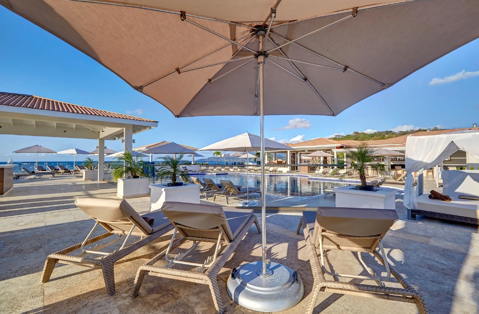 Poolside loungers and umbrellas face the ocean at Royalton Grenada.