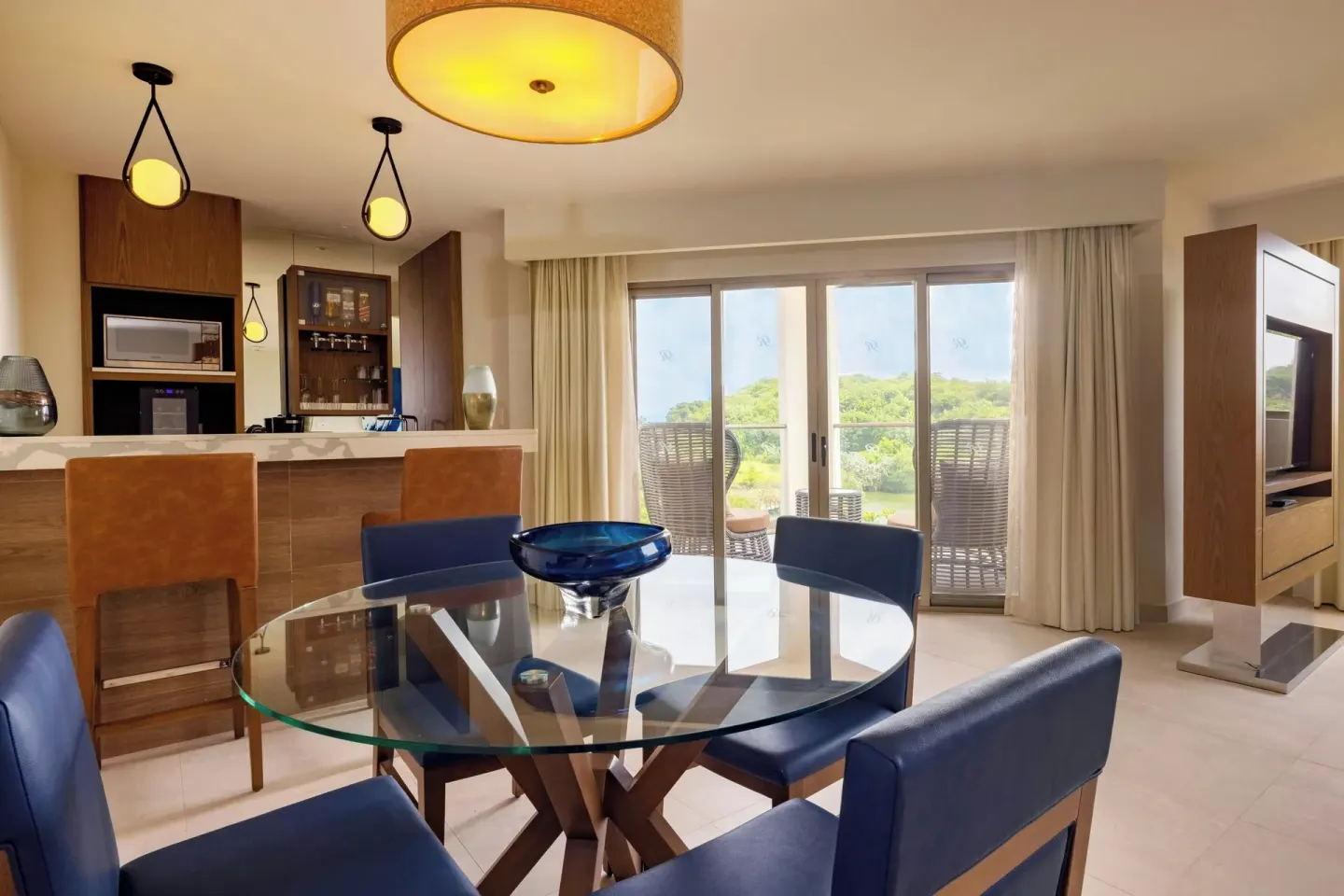 Suite dining area with glass table and balcony doors at Royalton Grenada.
