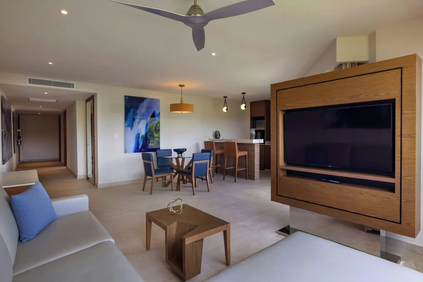 Modern suite living and dining area with a TV and kitchenette at Royalton Grenada.