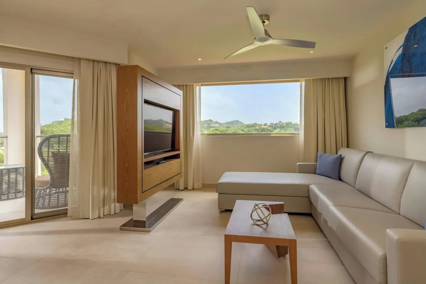 Suite lounge with sectional sofa, TV, and hillside view at Royalton Grenada.