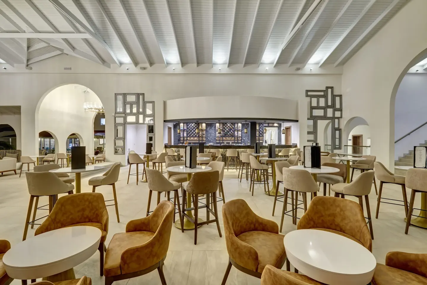 Lobby bar seating with round tables and a back bar at Royalton Grenada.
