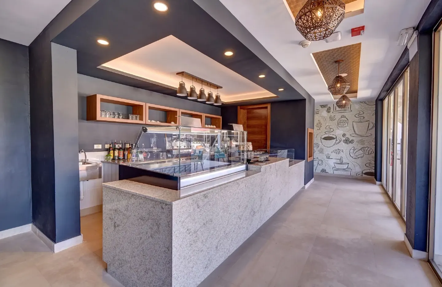 Cafe counter with glass display cases and coffee wall art at Royalton Grenada.