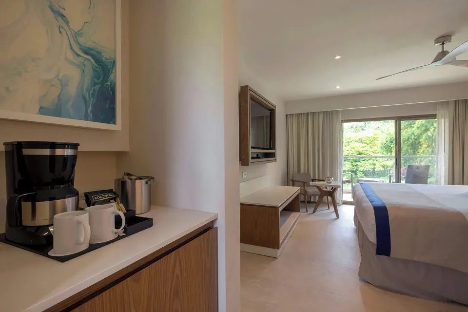 Suite king bedroom with coffee setup and garden-facing balcony at Royalton Grenada.