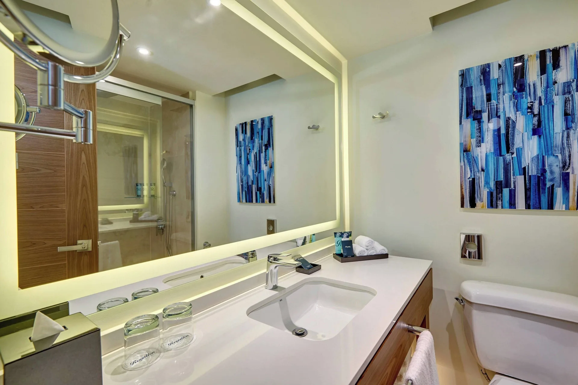 Luxury Room bathroom at Royalton Grenada with sink, toilet, lighted mirror, and shower reflection.