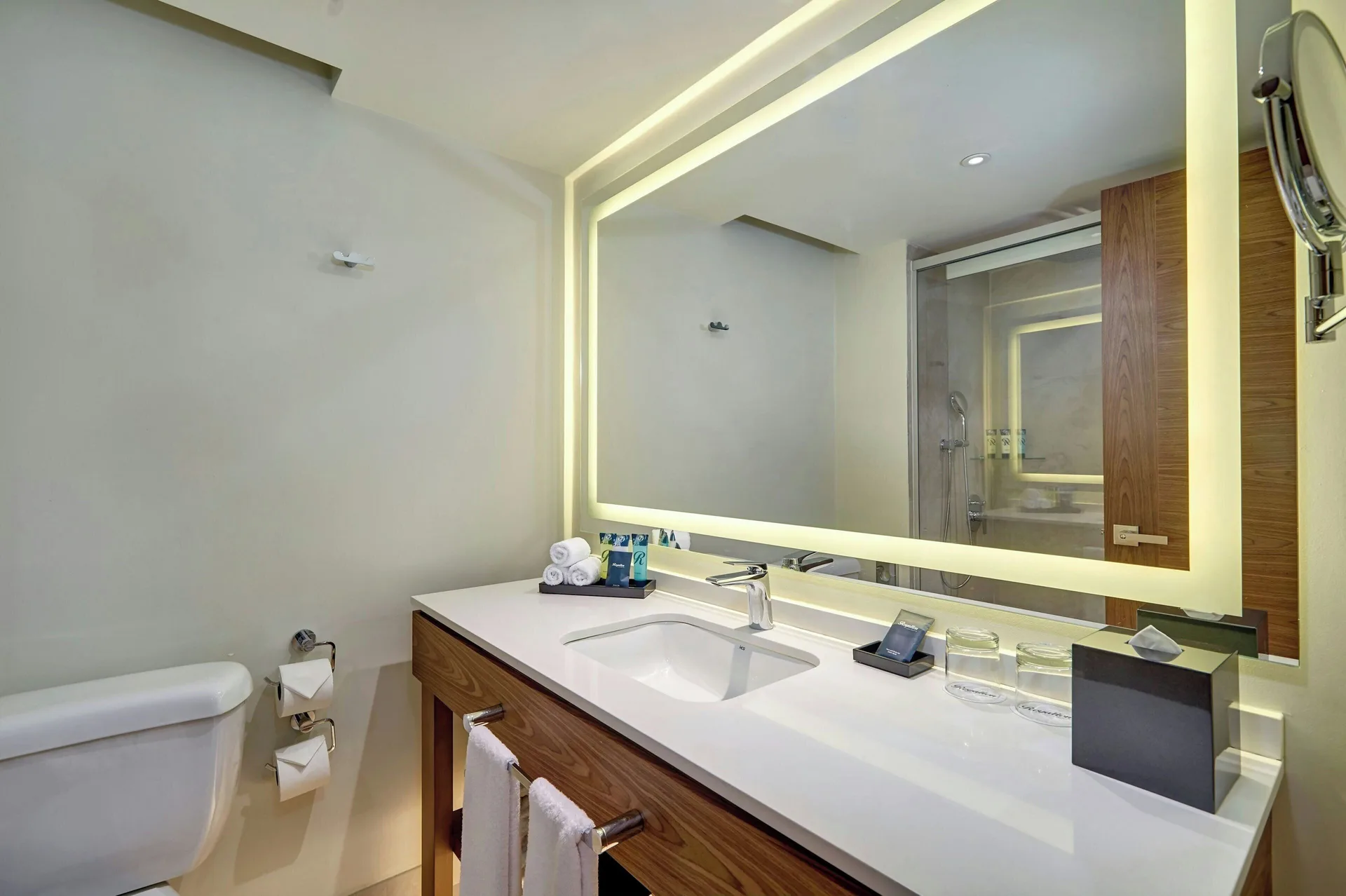 Luxury Room bathroom with long vanity, toilet and illuminated mirror at Royalton Grenada.