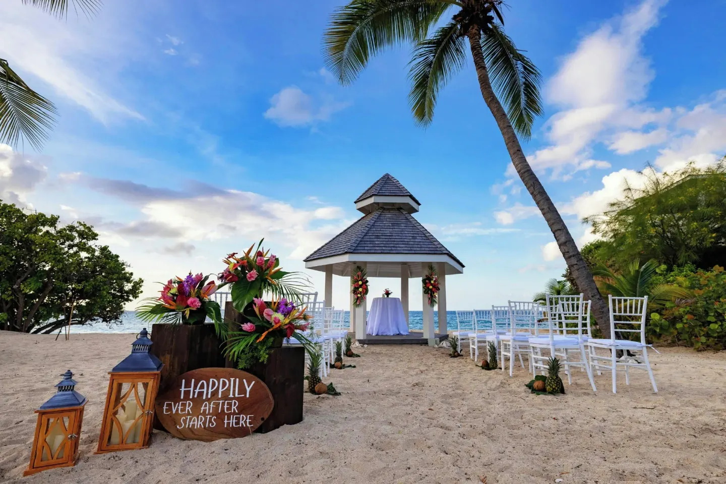 Beach wedding setup with white chairs, floral decor, and a gazebo at Royalton Grenada.