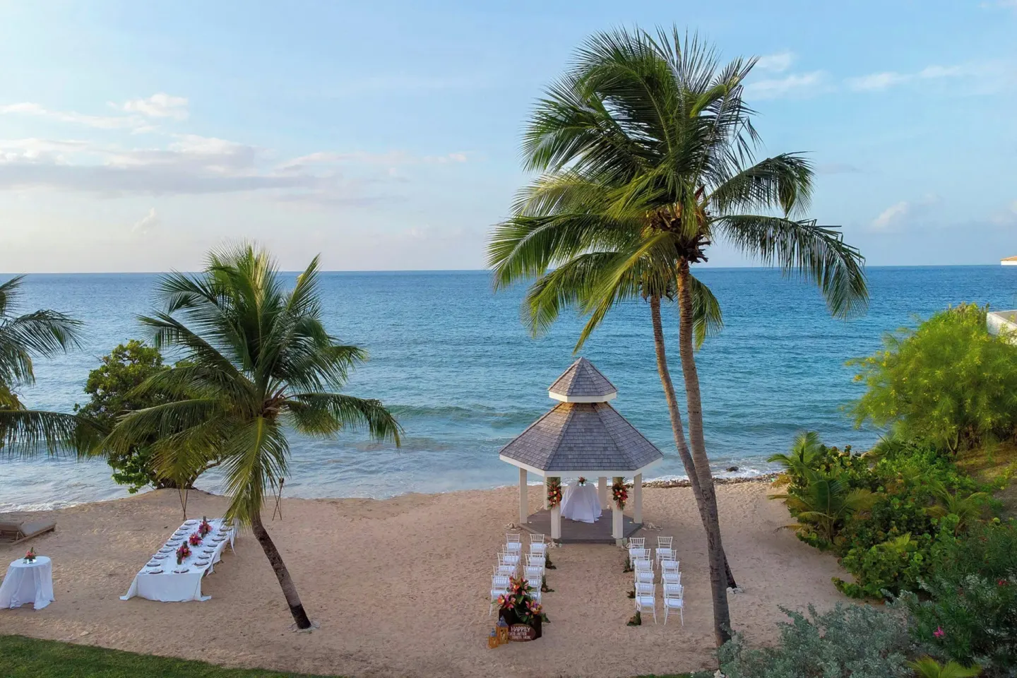 Aerial view of a beach wedding ceremony setup beside palm trees at Royalton Grenada.