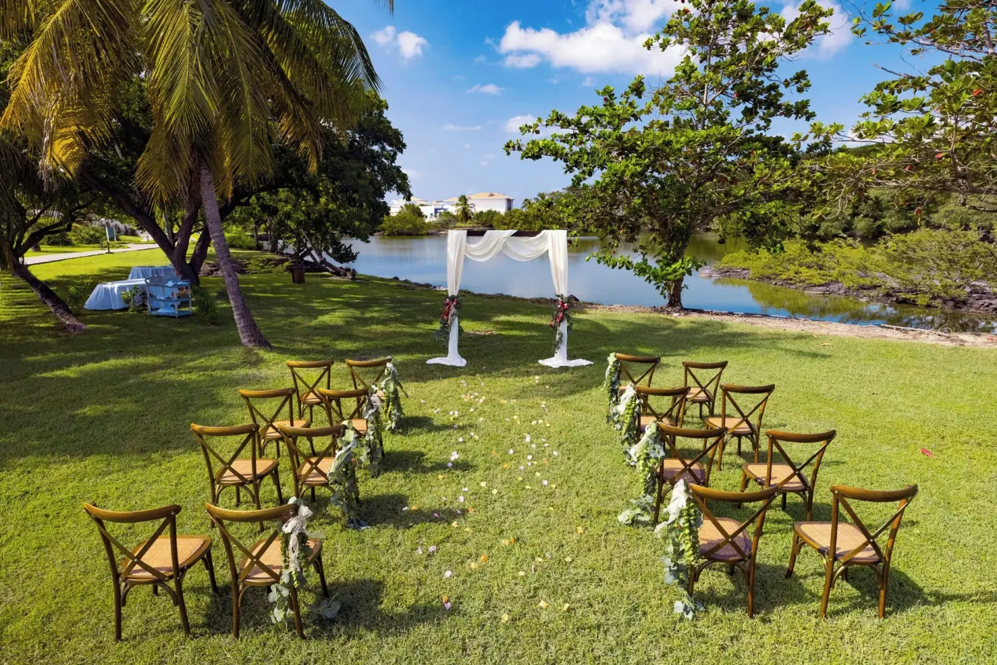 Garden wedding ceremony setup with wooden chairs by a lagoon at Royalton Grenada.