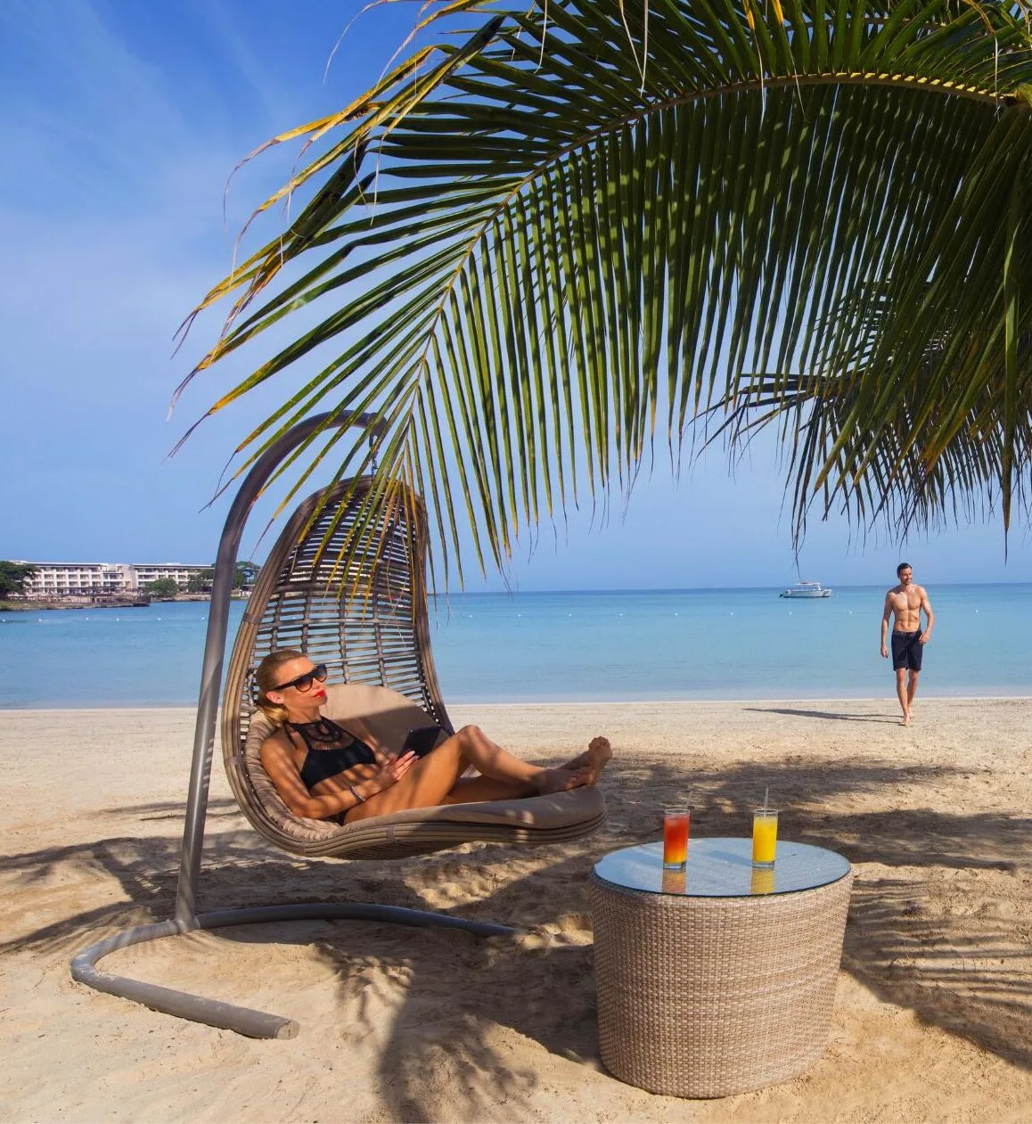Guest relaxing in a hanging beach chair under palms at Royalton Hideaway Negril.