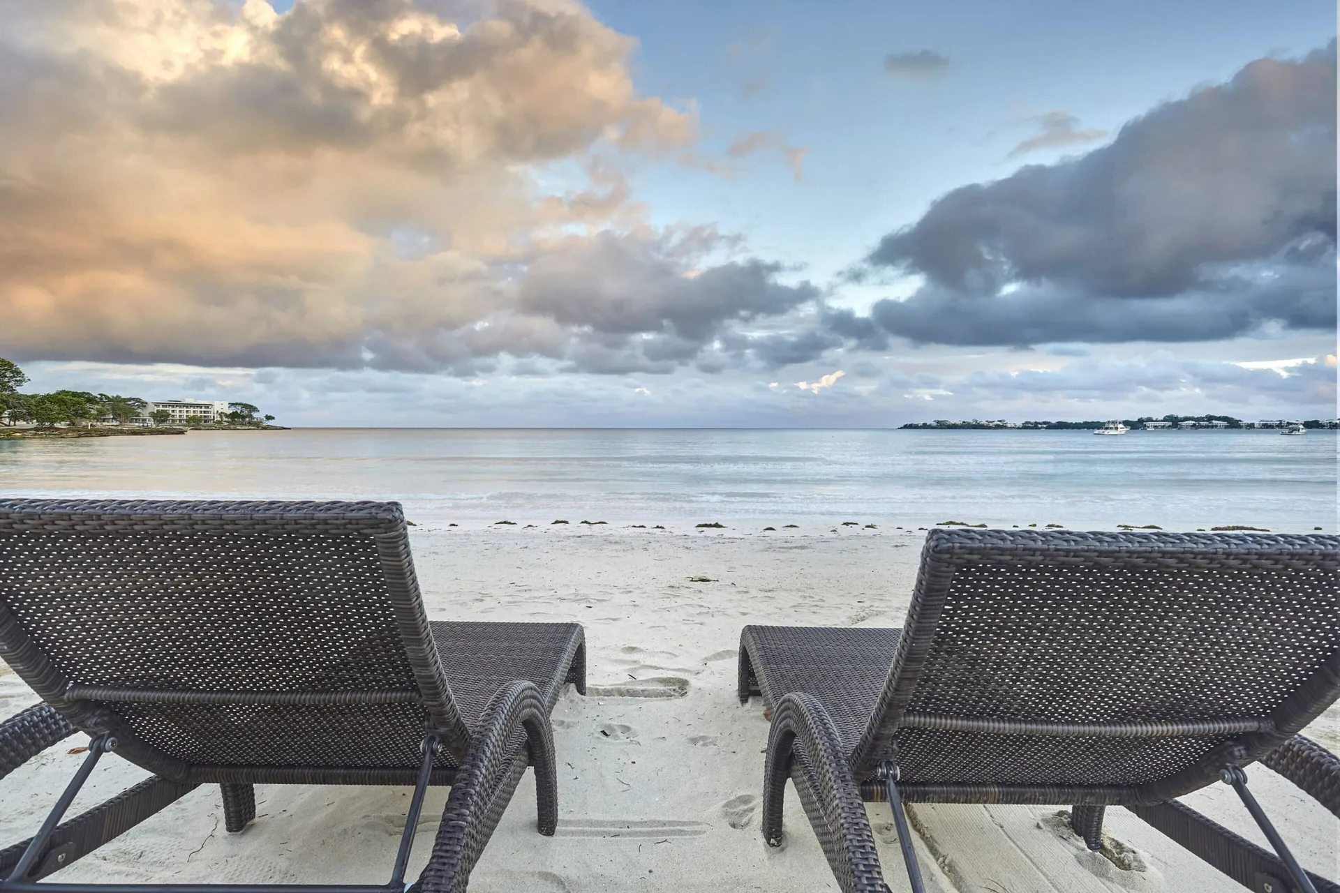 Two wicker lounge chairs facing the beach and calm sea at Royalton Hideaway Negril.