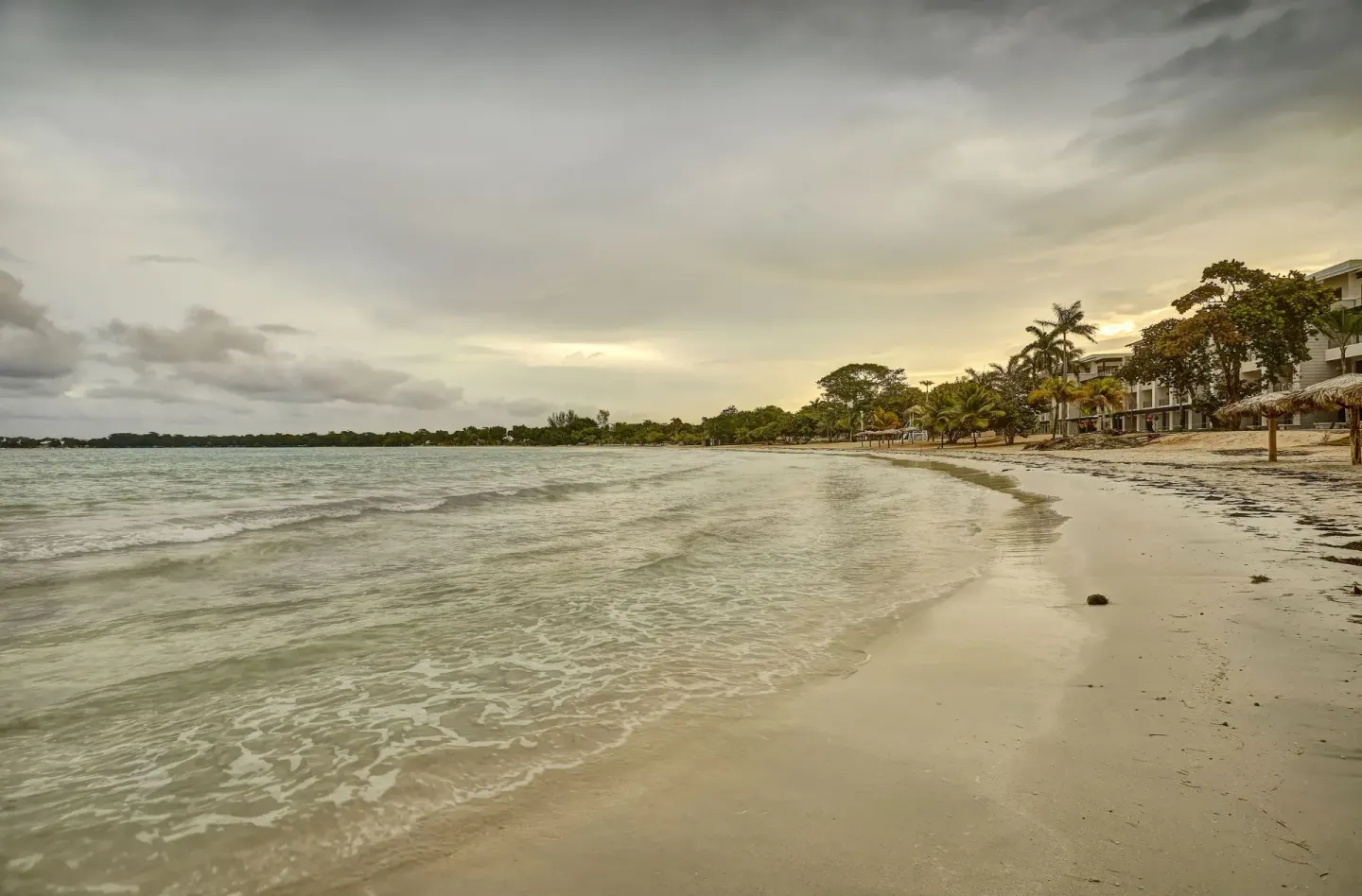Curving sandy beach with gentle waves and resort buildings at Royalton Hideaway Negril.
