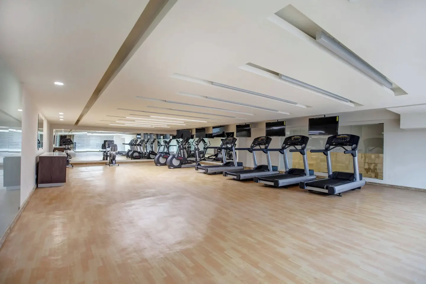Fitness room with treadmills, cardio machines, and wood flooring at Royalton Hideaway Negril.