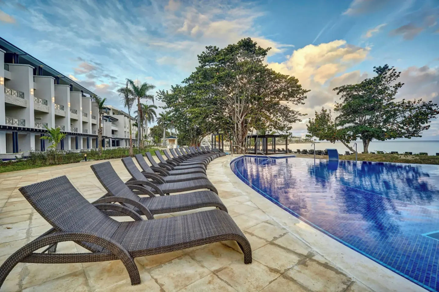Poolside loungers curve beside the main pool and resort building at Royalton Hideaway Negril.