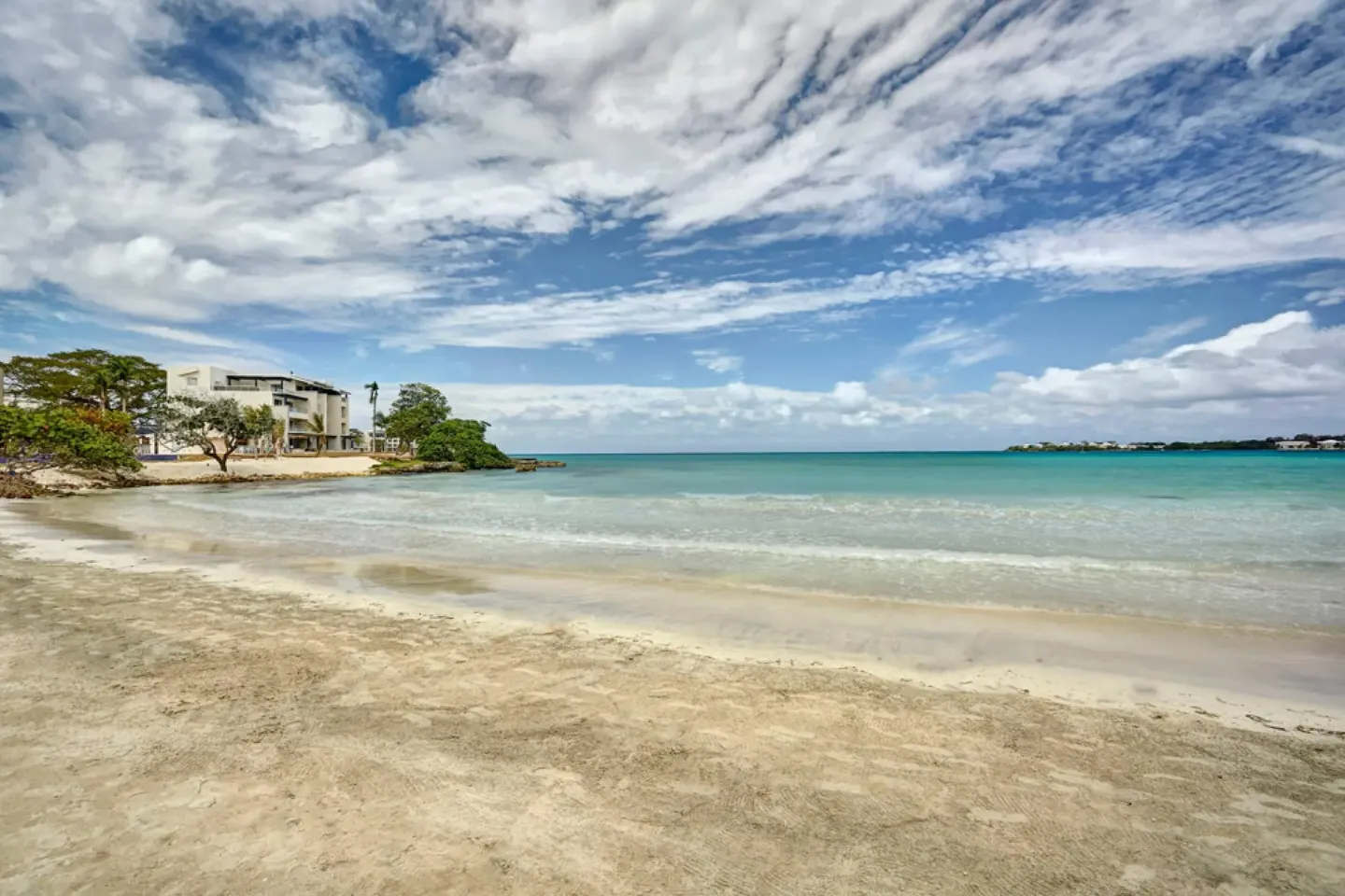 Wide sandy beach, turquoise water and partly cloudy sky at Royalton Hideaway Negril.