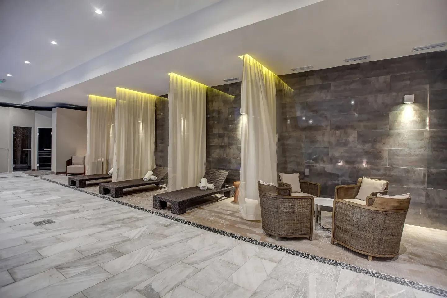 Curtained relaxation loungers and wicker chairs in the spa at Royalton Hideaway Negril.