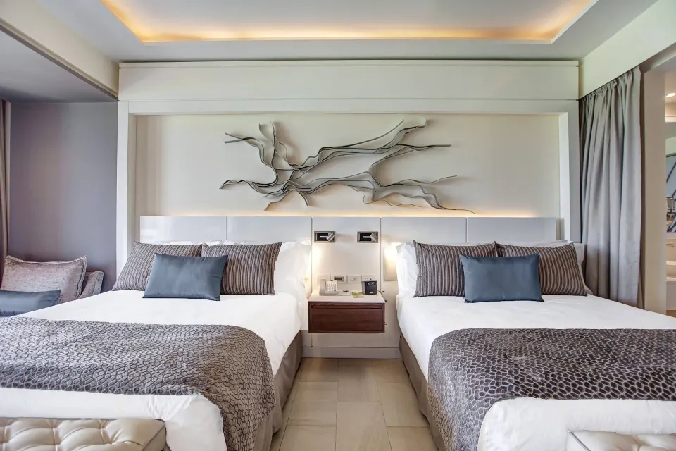 Luxury Junior Suite Ocean View with two beds and sculptural wall art at Royalton Hideaway Negril.