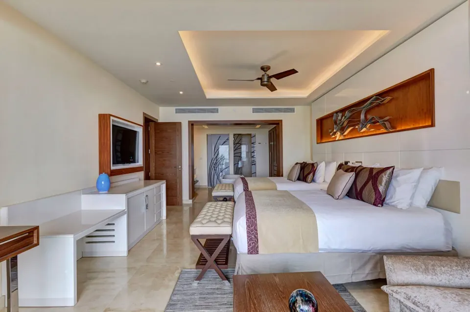 Bedroom with two beds and TV console in a suite at Royalton Hideaway Negril.