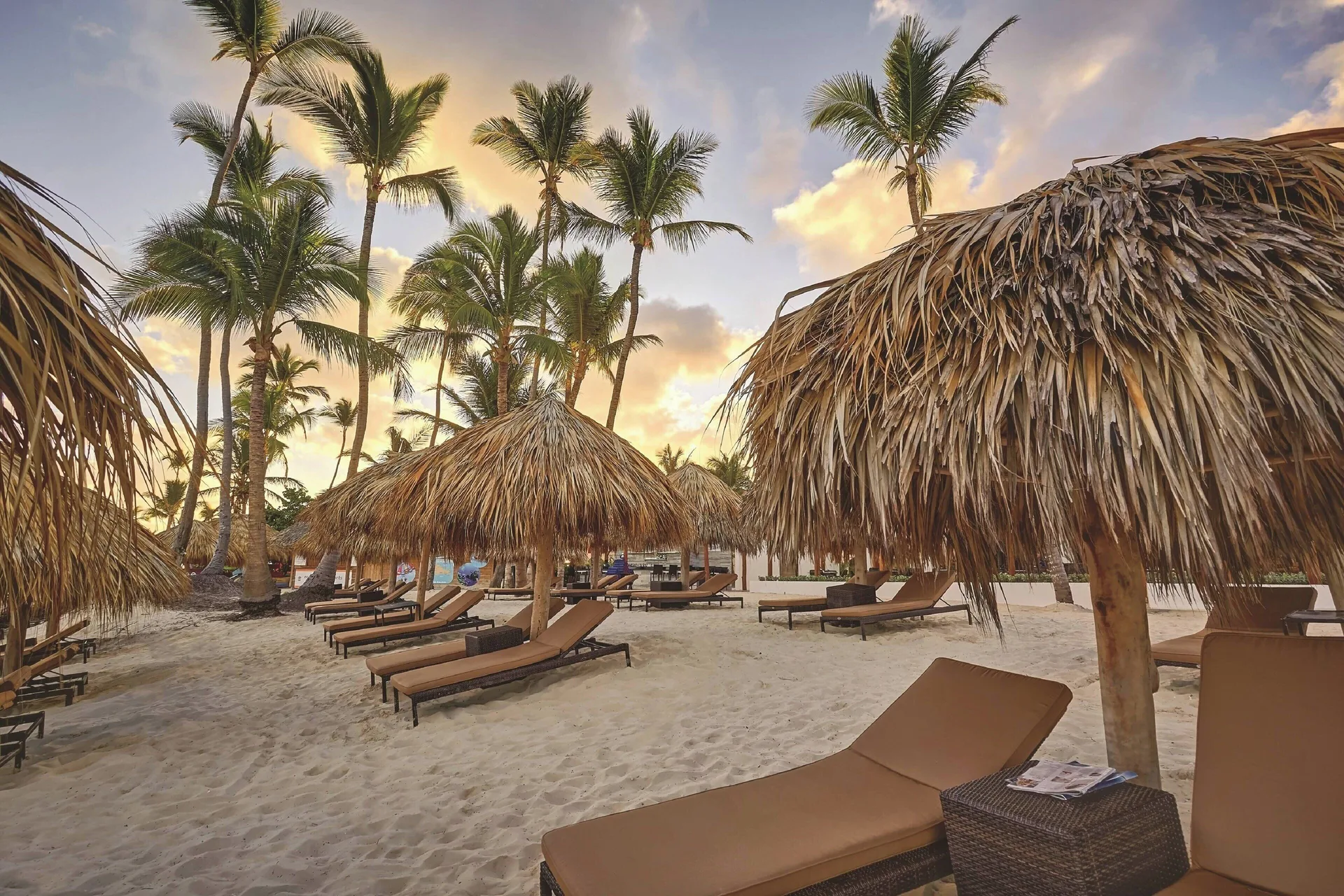 Thatched beach palapas and lounge chairs at Royalton Hideaway Punta Cana Resort & Casino.