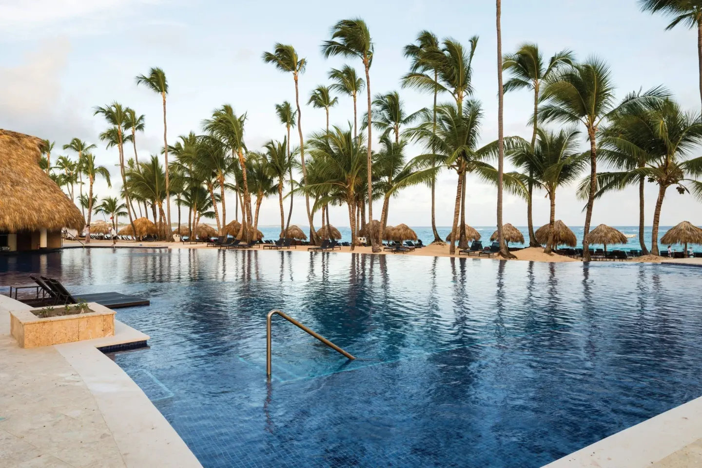 Beachfront pool with palms and palapas at Royalton Hideaway Punta Cana Resort & Casino.