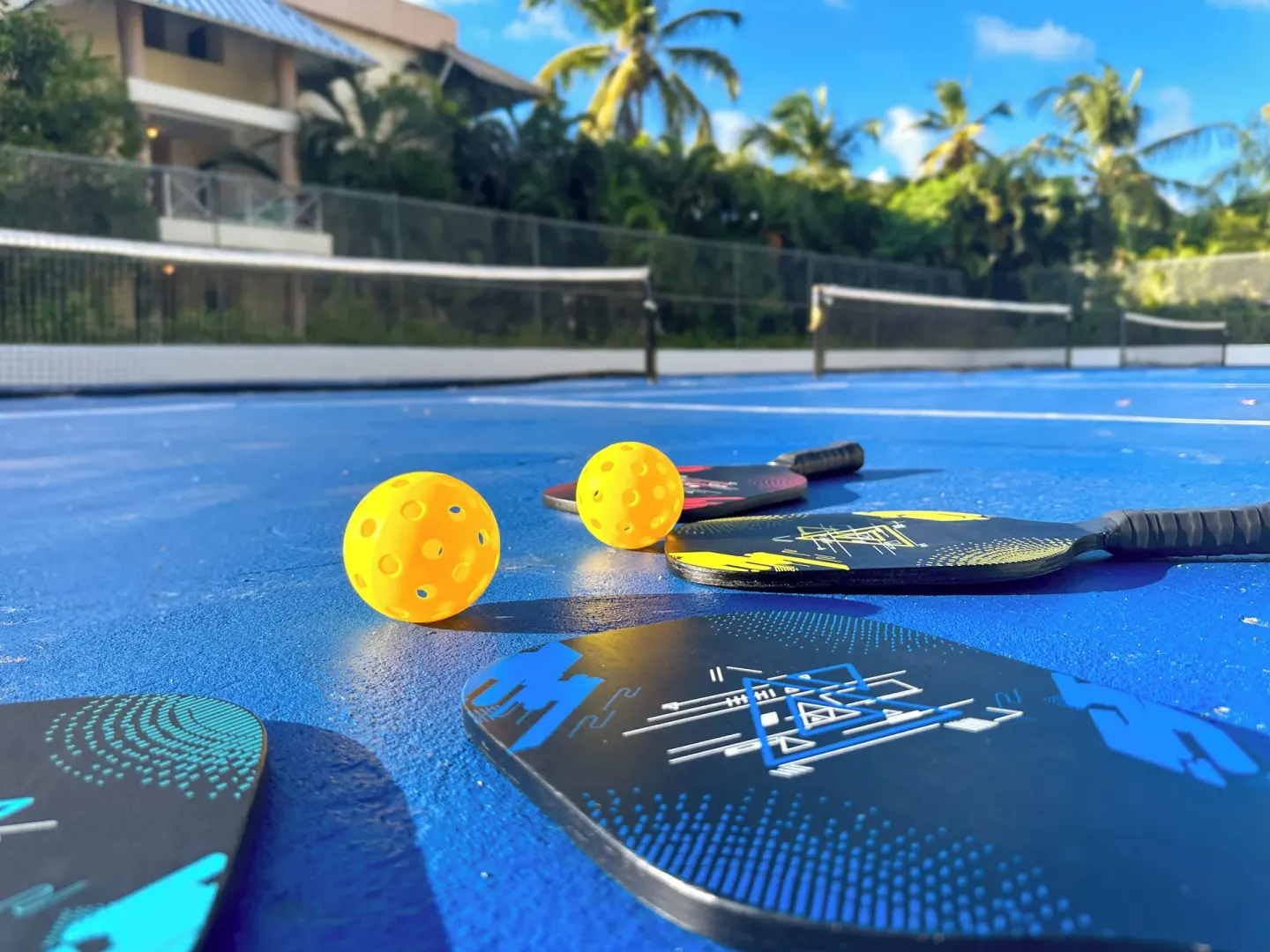Pickleball paddles and balls on a blue court at Royalton Hideaway Punta Cana Resort & Casino.