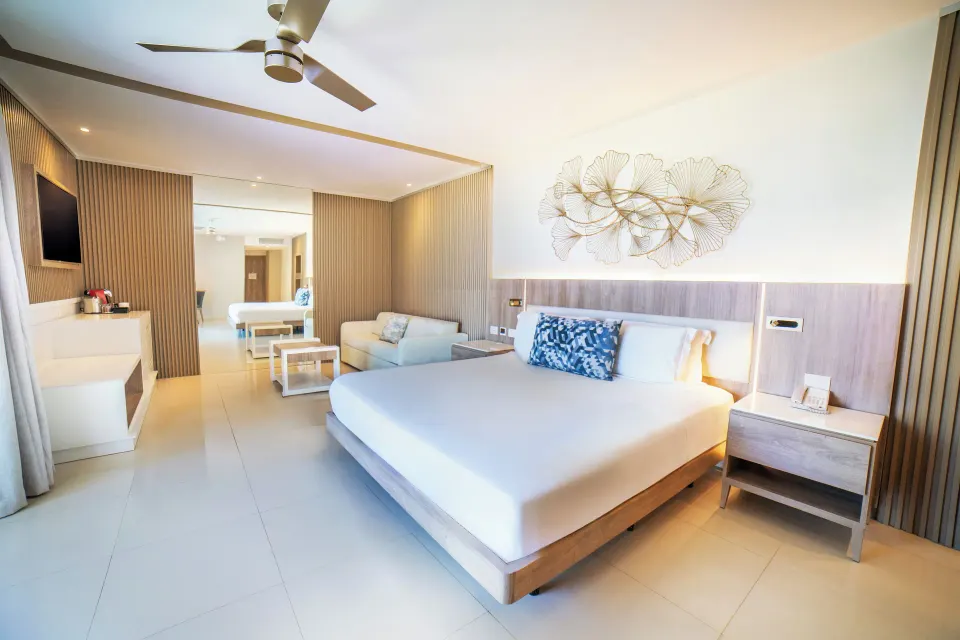 King bed in the Honeymoon Jacuzzi Suite Diamond Club at Royalton Hideaway Punta Cana Resort & Casino with sofa and wall art.
