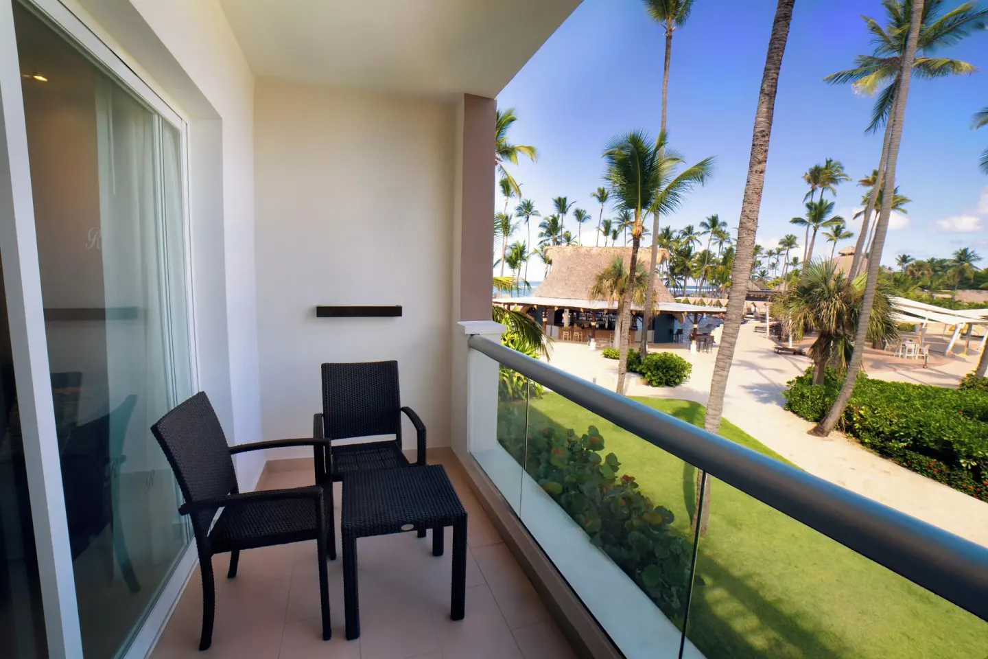 Luxury Room balcony with chairs and palm-lined resort view at Royalton Hideaway Punta Cana Resort & Casino.