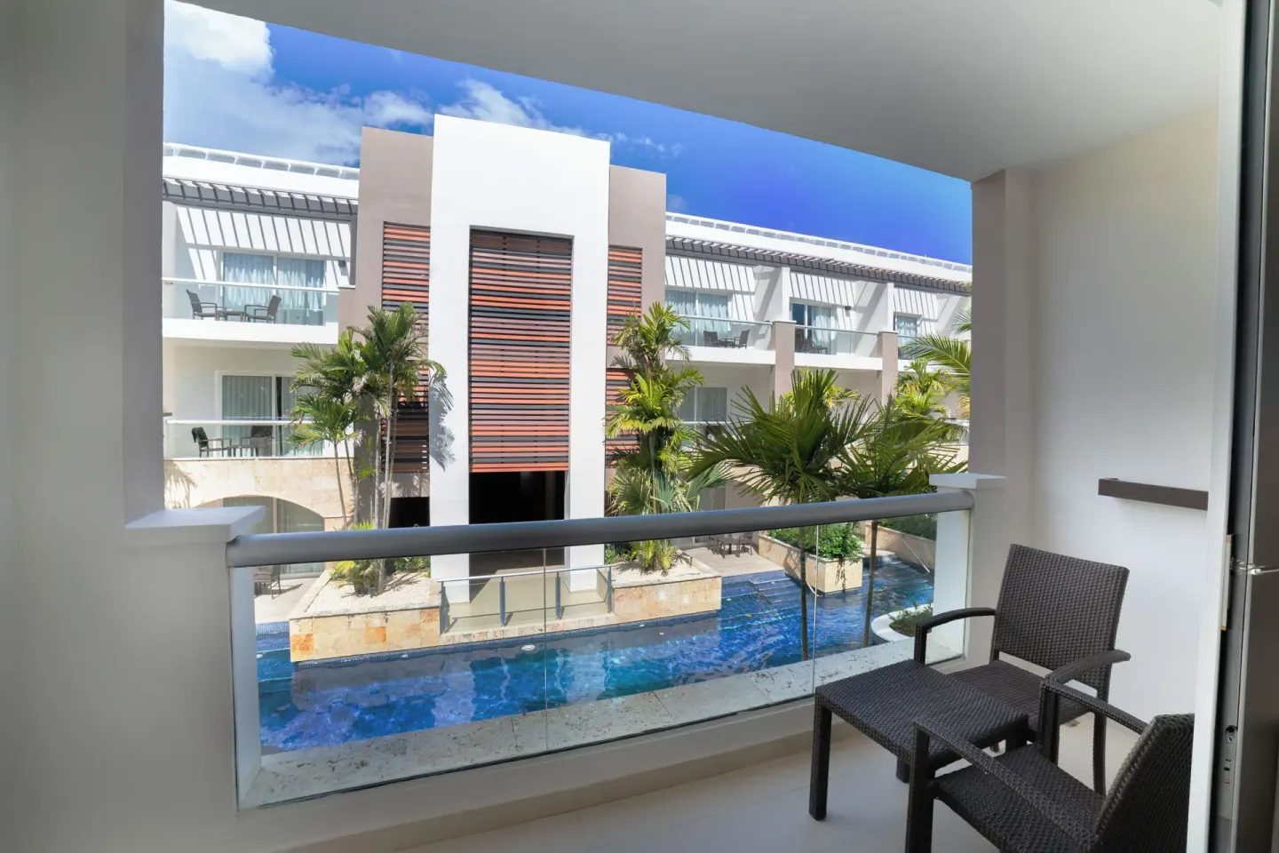 Luxury Room balcony with chairs overlooking a pool area at Royalton Hideaway Punta Cana Resort & Casino.