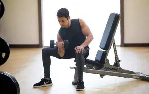 Man lifting a dumbbell beside a workout bench at Royalton Hideaway Saint Lucia.