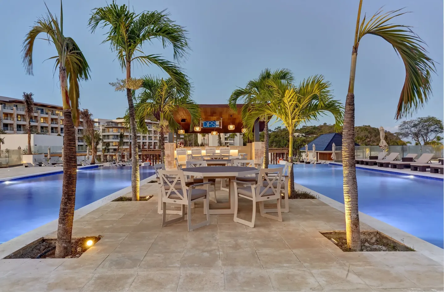 Palm-lined poolside seating and bar at dusk at Royalton Hideaway Saint Lucia.