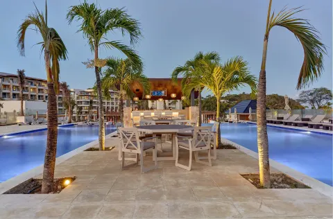Palm-lined poolside seating and bar at dusk at Royalton Hideaway Saint Lucia.