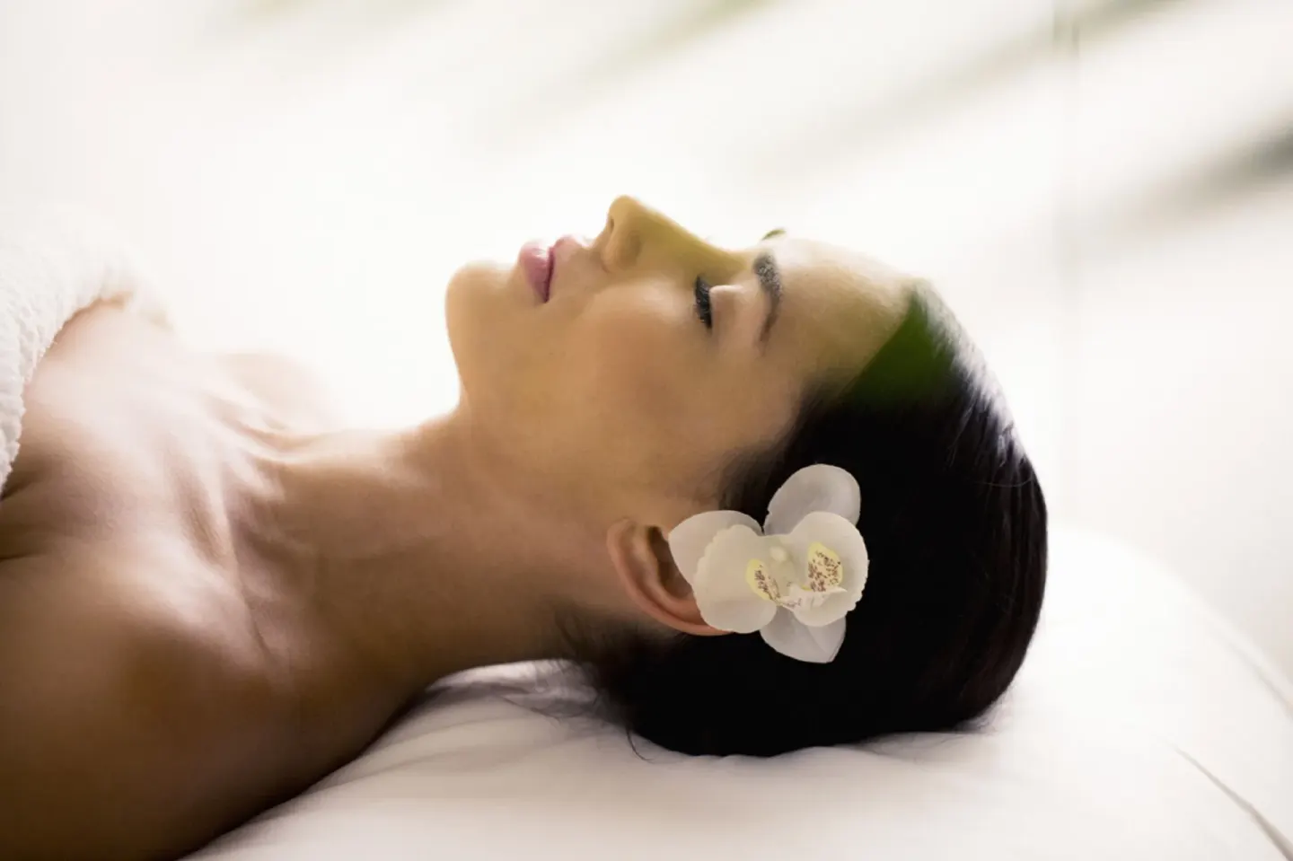 Woman resting with a white orchid by her ear at Royalton Hideaway Saint Lucia.