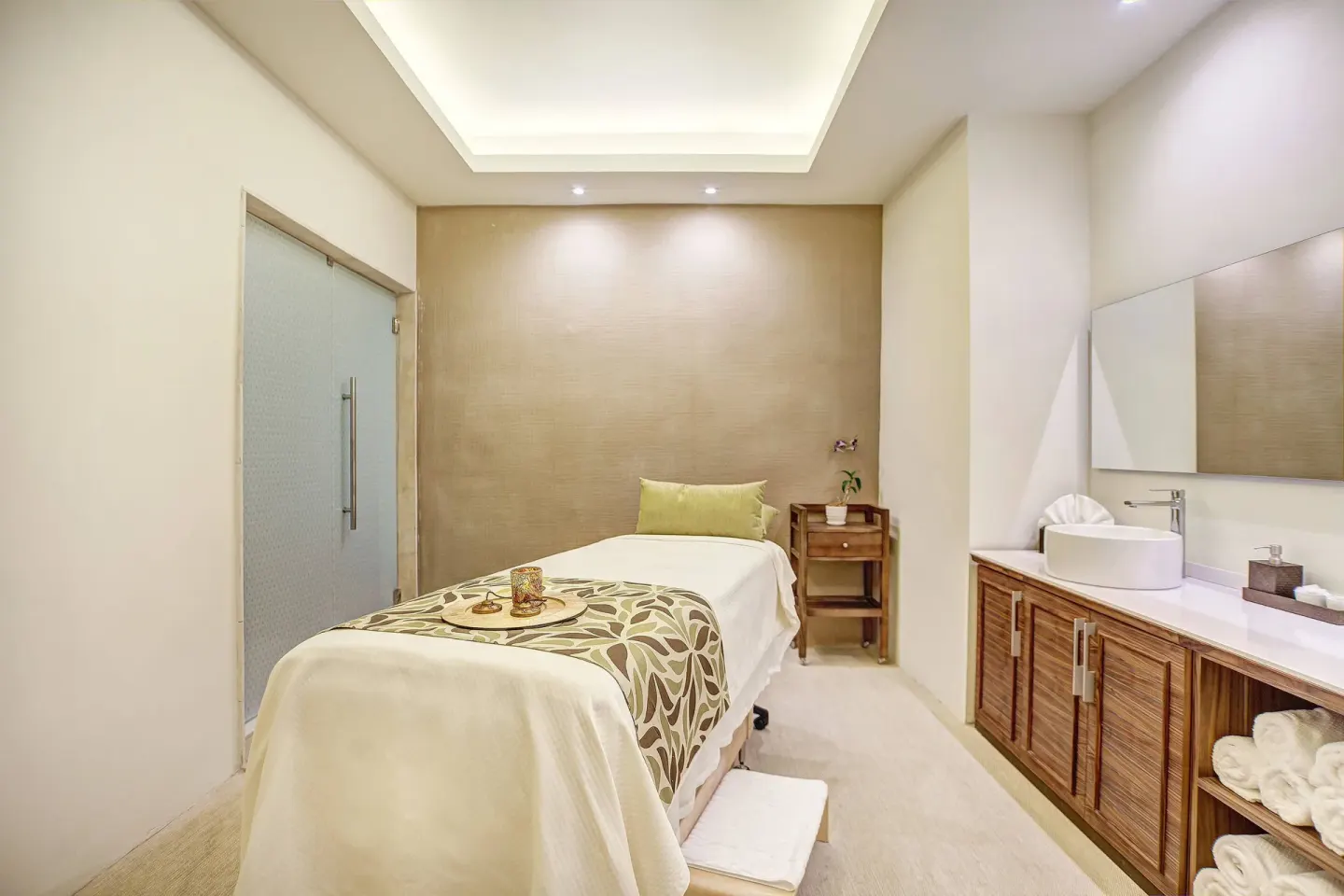 Spa treatment room with bed, sink, towels, and wood cabinetry at Royalton Hideaway Saint Lucia.