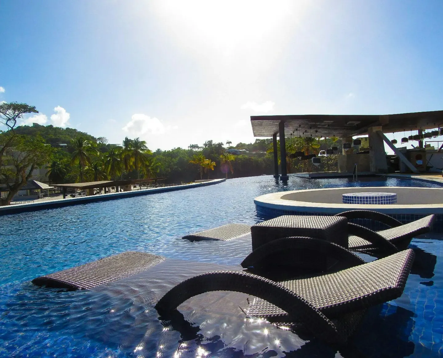 Sunlit pool with submerged lounge chairs at Royalton Hideaway Saint Lucia.