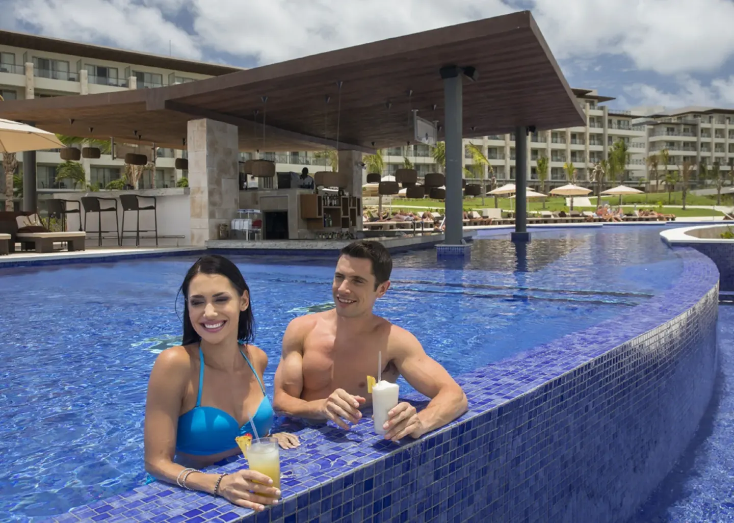Guests holding drinks in the pool beside the swim-up bar at Royalton Hideaway Saint Lucia.