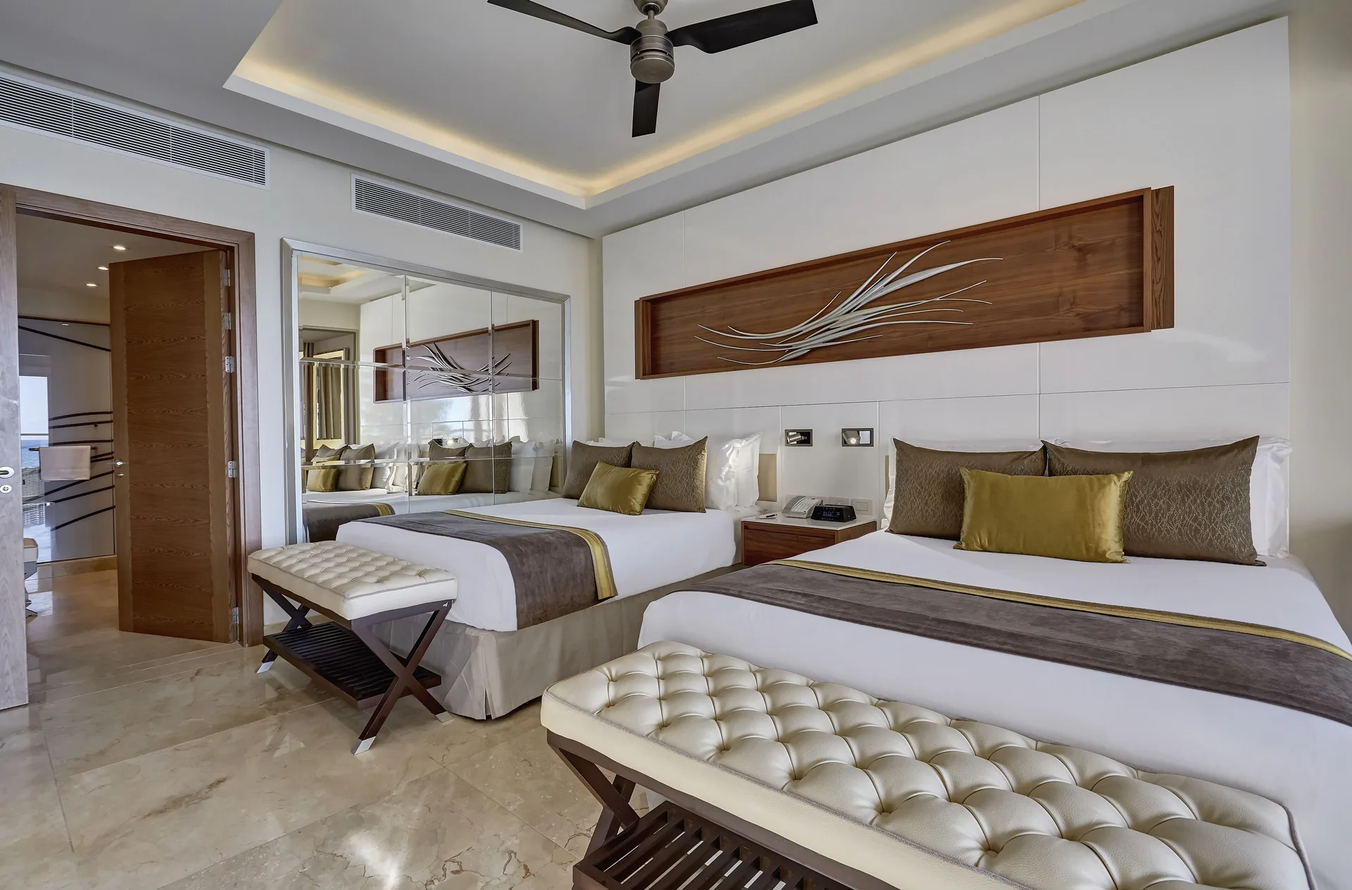 Two-bed bedroom with benches and mirrored wall at Royalton Hideaway Saint Lucia.