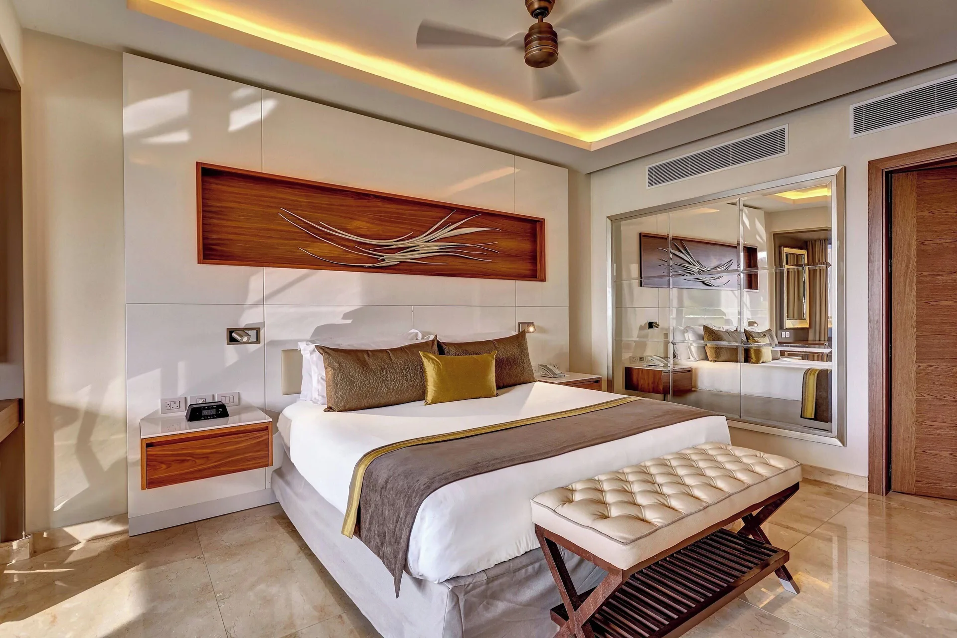 King bedroom with tufted bench and mirrored wall at Royalton Hideaway Saint Lucia.