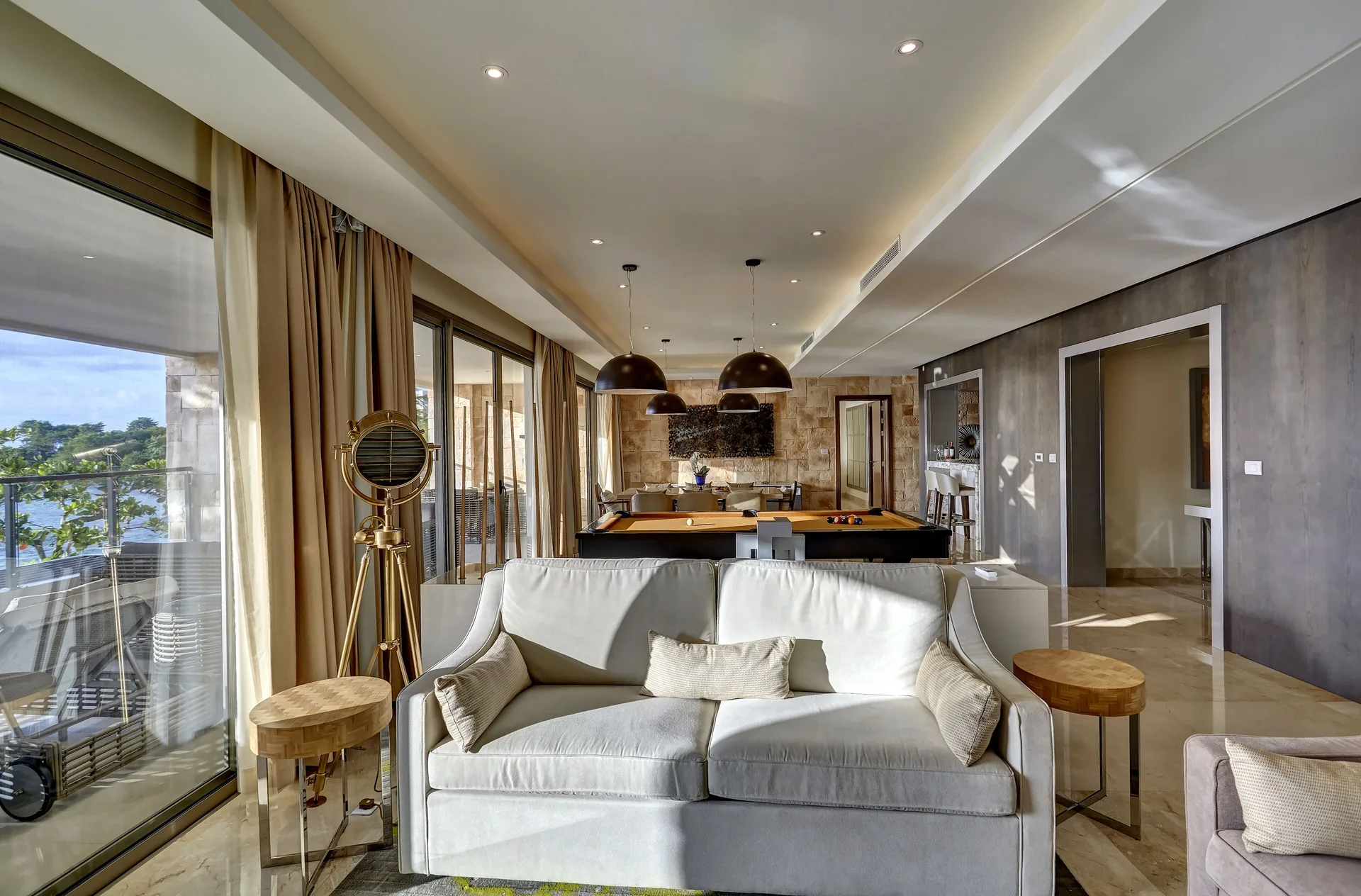Suite living room with sofa, pool table, and balcony doors at Royalton Hideaway Saint Lucia.