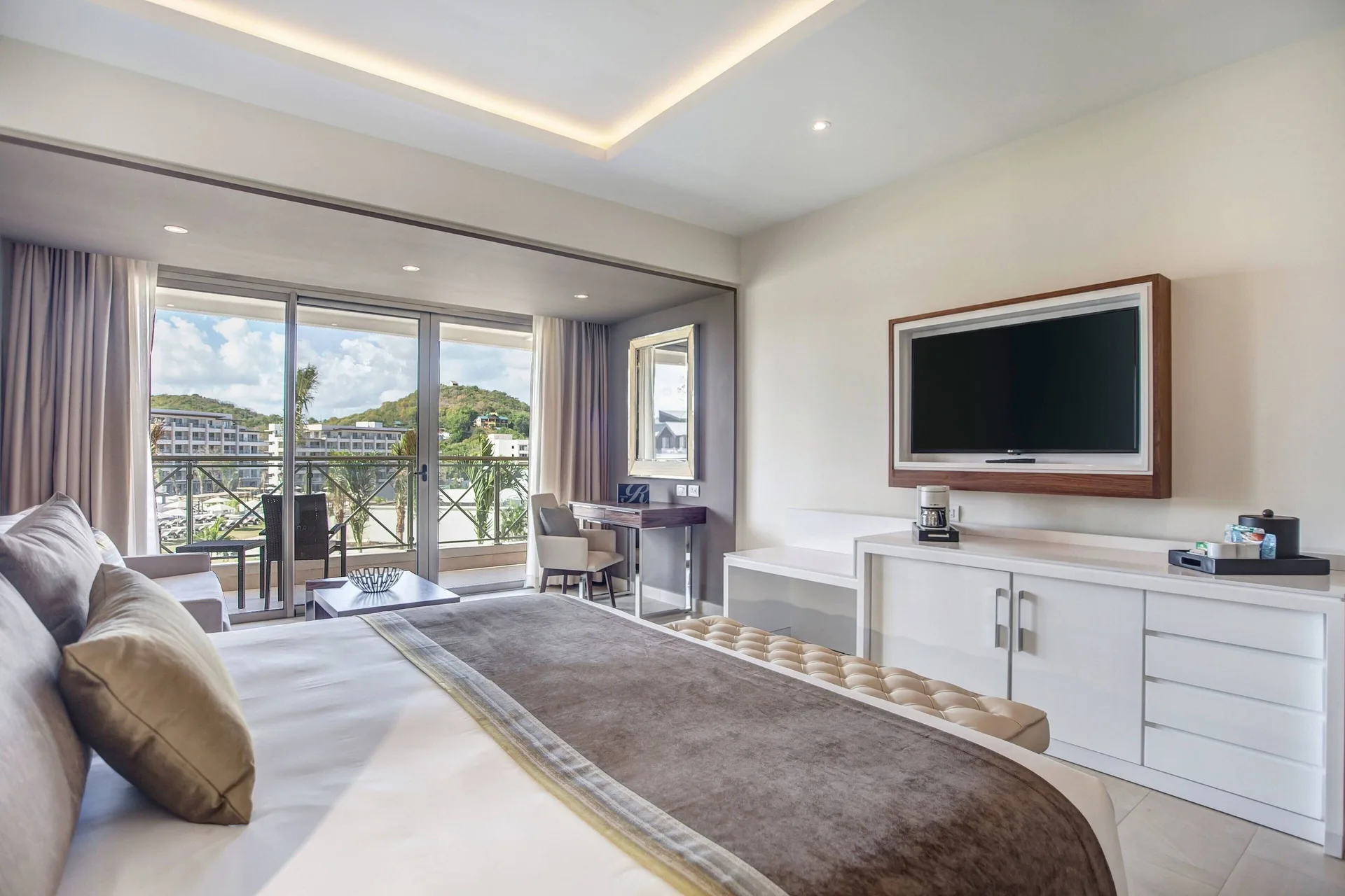 Luxury Family Suite Ocean View Diamond Club bed, TV, and balcony at Royalton Hideaway Saint Lucia.