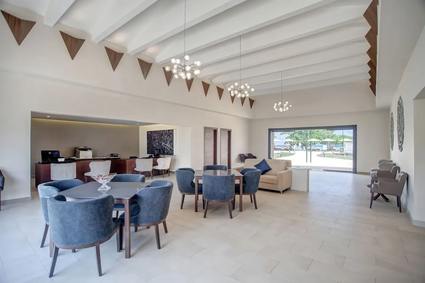 Bright lounge with blue chairs, sofas, and a window to the grounds at Royalton Negril.
