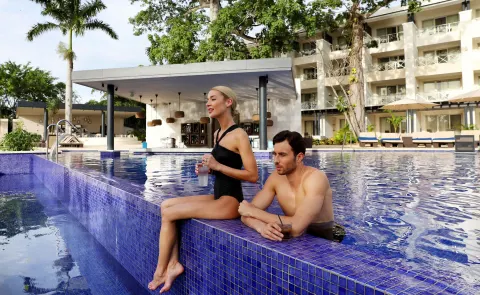 Couple relaxing with drinks in a blue-tiled pool at Royalton Negril.