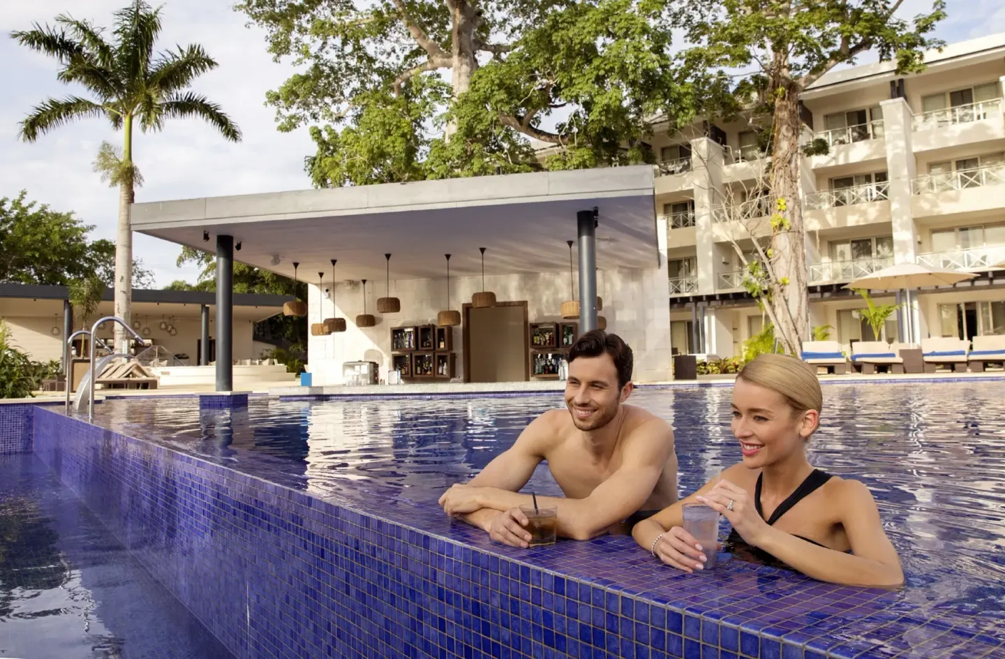 Couple holding drinks at the pool edge at Royalton Negril.