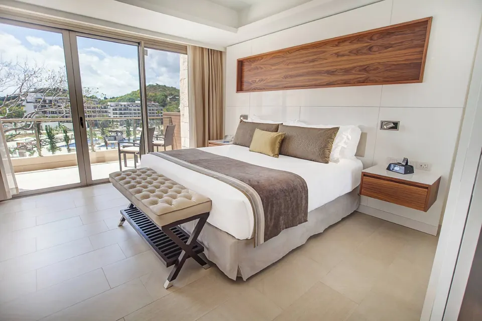 Luxury Family Suite Ocean View king bed beside sliding balcony doors at Royalton Negril.