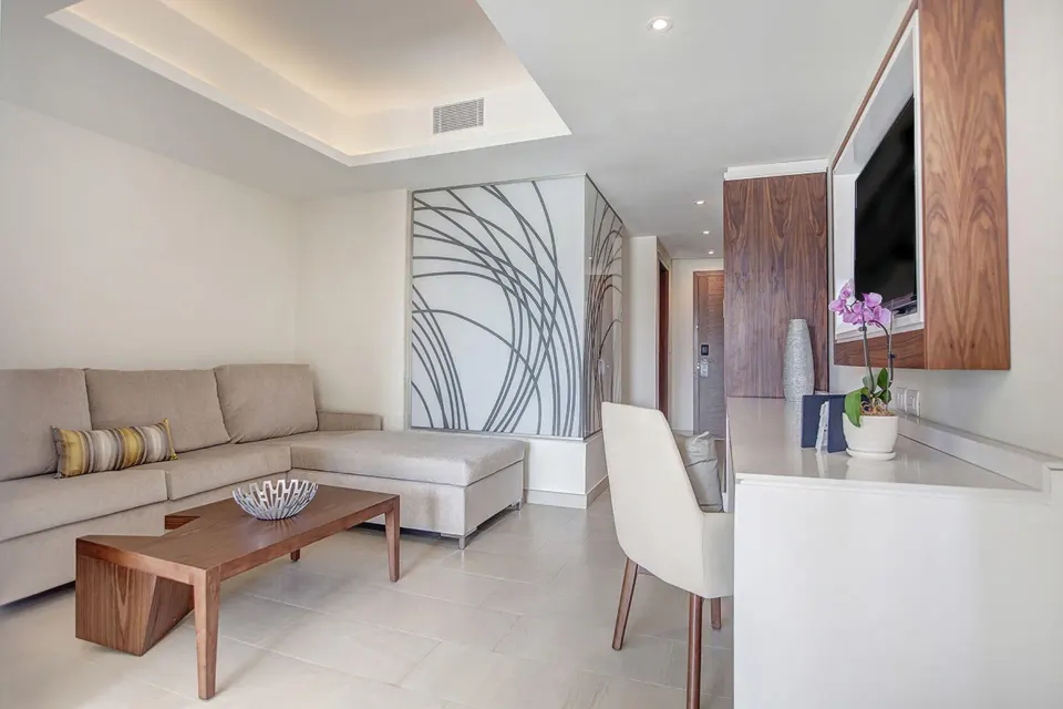 Luxury Family Suite Ocean View living area with desk and wall-mounted TV at Royalton Negril.